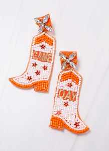 Game Day orange and white beaded earrings.  Each earring is shaped like a cowboy boot and is beaded with orange and white beads, five sequin stars, and star accents on the posts.  One earring says game and the other say day.