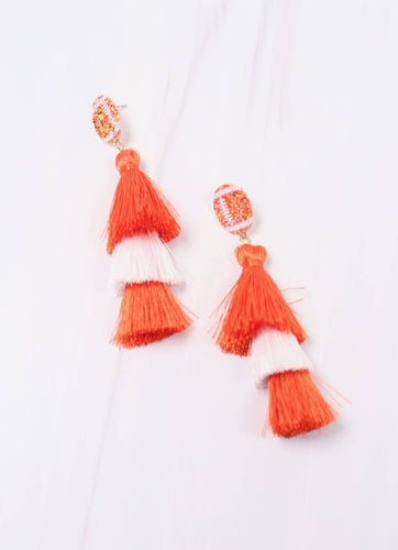 Two orange and white tassle earrings. Each is set with a glittered football post and then an orange tassle, a white tassle, and one final orange tassle.  These earrings are super cute for football and game days.