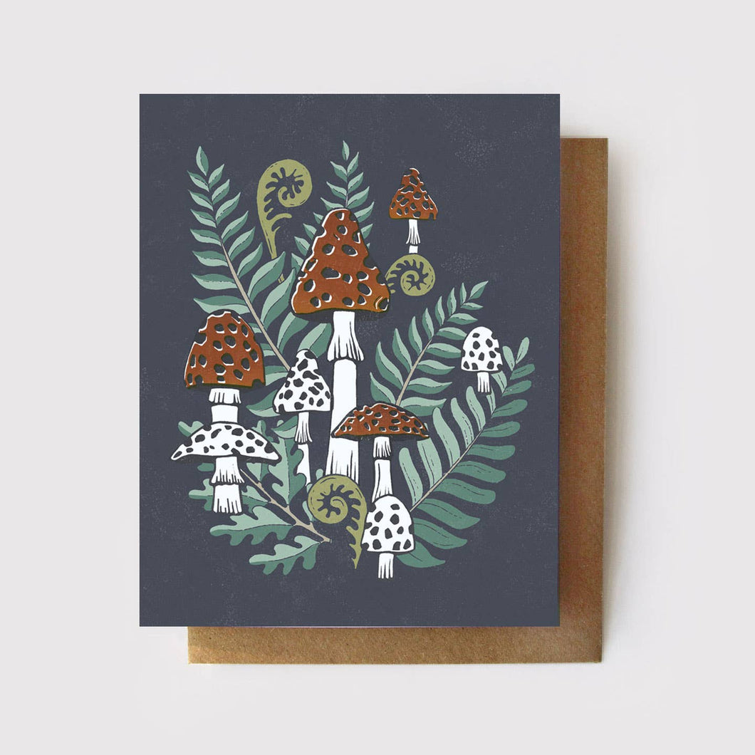 Greeting card with slate background color with varying sizes of toadstools and ferns.  Four toadstools are white stemmed with red caps with dots and four are white with slate dots.  The fern leaves are varying shades of greens.