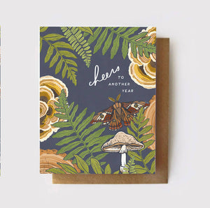 Gorgeous greeting card with slate background, overlain with  green ferns, cream colored and turkey tail mushrooms, tree rings, and a beautifully colored polyphemus moth.